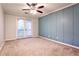 Bedroom with ceiling fan, tan carpet, blue accent wall, and glass patio doors to a balcony at 38 Saint Claire Ne Ln, Atlanta, GA 30324