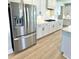 The kitchen featuring a stainless steel refrigerator, white cabinets, and light wood floors at 738 Crossroad Ct, Powder Springs, GA 30127
