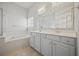 Bright bathroom features a soaking tub, shower, and double vanity with grey cabinets at 6329 Edgewater Cv, Fairburn, GA 30213