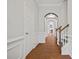 Inviting hallway with hardwood floors, elegant archways, and classic wainscoting leading to staircase at 6329 Edgewater Cv, Fairburn, GA 30213