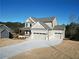 Two-story house with three-car garage, covered porch, and landscaping at 1129 Red Oak Blvd, Loganville, GA 30052