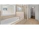 Spa-like bathroom with soaking tub, walk-in shower, and beige tile at 7470 Flintlock Way, Alpharetta, GA 30005