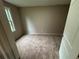 A carpeted bedroom featuring tan walls, a light and a large window providing natural light at 5544 Whispering Swan Ct, Douglasville, GA 30135