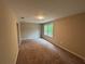 A carpeted bedroom featuring tan walls, a light and a large window providing natural light at 5544 Whispering Swan Ct, Douglasville, GA 30135