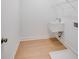 A small, functional laundry area featuring a wall-mounted sink, wooden floors, and a wire rack for storage at 41 Bennett Farm Dr, Loganville, GA 30052