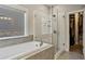 Bright bathroom with a soaking tub, glass-enclosed shower, and walk-in closet access at 1995 Woodmont Dr, Douglasville, GA 30135
