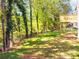 View of tree line and lawn in backyard with corner of wooden deck visible in the distance at 6462 Beaver Creek Trl, Atlanta, GA 30349