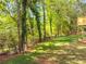 View of tree line and lawn in backyard with corner of wooden deck visible in the distance at 6462 Beaver Creek Trl, Atlanta, GA 30349