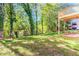 View of tree line and lawn in backyard with corner of wooden deck visible in the distance at 6462 Beaver Creek Trl, Atlanta, GA 30349
