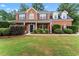 Charming two-story red brick home featuring a well-manicured lawn and inviting front porch with classic columns at 1500 Terminal Ct, Mcdonough, GA 30252