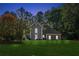 Charming gray two-story home with a manicured lawn and mature trees offering curb appeal at dusk at 1210 Swan Mill Ct, Suwanee, GA 30024