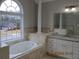 Bright bathroom features a soaking tub under a large window, and double vanity with granite countertops at 354 Mansfield Way, Stockbridge, GA 30281