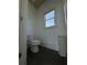 Compact half-bathroom with black tile floors and a window for natural light at 3450 Camellia Ln, Suwanee, GA 30024