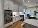 Bright kitchen features stainless appliances, hardwood floors, modern white cabinetry, and breakfast bar at 3450 Camellia Ln, Suwanee, GA 30024