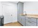 Bright laundry room with wood floor, gray cabinets, butcher block countertop, and stainless steel washer at 1377 Oak Grove Dr, Decatur, GA 30033