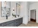 Modern bathroom with dual sinks, gray cabinets, elegant lighting, and a view into the adjoining water closet at 971 Washington Sw Pl, Atlanta, GA 30314