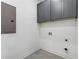 An efficient laundry area with gray cabinets and tiled floor, electrical panel, and various connection points at 971 Washington Sw Pl, Atlanta, GA 30314