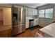 Open-concept kitchen with stainless steel refrigerator, white cabinets, and hardwood flooring at 3380 Lake Valley Nw Rd, Atlanta, GA 30331
