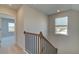 Well-lit hallway with carpet flooring, black metal railing, and a view through doorways to other rooms at 125 Belvedere Rd, Mcdonough, GA 30253
