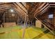 Unfinished attic space with exposed wooden beams, green carpet, and a small window providing natural light at 1366 Emory Ne Rd, Atlanta, GA 30306