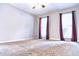 An empty bedroom with carpet floors and two windows with red curtains at 295 Whitby Dr, Douglasville, GA 30134