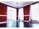 Dining room featuring hardwood floors, red accent wall, crown molding, and ample natural light at 295 Whitby Dr, Douglasville, GA 30134