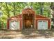A large barn-style garage, painted red with two white doors, nestled among trees provides ample storage space at 2130 Perkerson Mill Rd, Austell, GA 30106