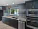 Stylish kitchen with dark cabinets, stainless steel appliances, backsplash, and lake view from the window at 6095 Blackberry Ln, Buford, GA 30518