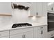 Modern kitchen with stainless steel gas range, white backsplash, and bright white cabinets at 7530 Homer Dr, Cumming, GA 30028