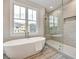 Bright bathroom with a modern tub next to a window and a glass-enclosed shower with tiled walls at 1697 Eastside Parc St, Atlanta, GA 30316
