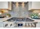 Close-up of a modern gas range with a decorative tile backsplash and stainless steel appliances at 1697 Eastside Parc St, Atlanta, GA 30316