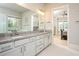 Bathroom featuring dual sinks, granite counters, and a view into the Primary bedroom at 255 Old Town Rd, Dacula, GA 30019