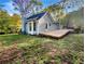 View of a wooden deck, chimney, and the rear of the home set on a spacious yard, backed by mature trees at 5394 Muirwood Pl, Powder Springs, GA 30127