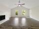 Bright living room with fireplace, dark wood floors, ceiling fan, and large windows at 5394 Muirwood Pl, Powder Springs, GA 30127