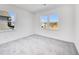 This is a light-filled bedroom with gray carpet and two large windows offering views of the neighborhood at 93 Sheryl Way, Loganville, GA 30052