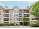 Condo building with multiple units, balconies, black railings, beige exterior, and manicured landscaping at 1850 Cotillion Dr # 3221, Dunwoody, GA 30338