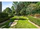 Lush green lawns and manicured hedges create a serene backyard, with a stone path for a peaceful stroll at 980 Fenimore Cir, Sandy Springs, GA 30350