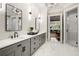 Stylish bathroom featuring marble tile, a double vanity, and mirrors, with a glimpse into the living room at 980 Fenimore Cir, Sandy Springs, GA 30350