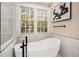 Bathroom featuring a freestanding tub, window, and marble-look tile at 980 Fenimore Cir, Sandy Springs, GA 30350