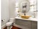 Stylish powder room with a gold vessel sink, decorative mirror, sconces, and wood-look floors at 980 Fenimore Cir, Sandy Springs, GA 30350