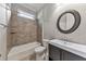 Bathroom with tub and shower combo, tiled walls, and round decorative mirror over a vanity at 2423 Rosapenna Nw Ln, Kennesaw, GA 30152