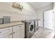 Bright laundry room features front load washer and dryer, ample storage, and neutral tones, combining function with style at 2423 Rosapenna Nw Ln, Kennesaw, GA 30152