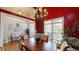 Elegant dining room with red walls, hardwood floors, and a chandelier providing a warm and inviting ambiance at 6054 Nebo Rd, Hiram, GA 30141