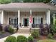 Inviting front porch with decorative columns, a swing, seating and manicured landscaping at 6054 Nebo Rd, Hiram, GA 30141