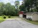 Exterior view featuring a red barn-style outbuilding with roll-up door and a tan storage building with a gravel parking area at 6054 Nebo Rd, Hiram, GA 30141