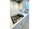 Close-up of a gas cooktop with stainless steel knobs, white cabinets, and quartz countertops at 735 Crossroad Sw Ct, Powder Springs, GA 30127