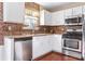 Kitchen with white cabinets, stainless steel appliances, and mosaic backsplash at 4118 Lost Springs Trl, Douglasville, GA 30135
