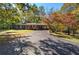 Brick ranch-style home with long driveway and carport surrounded by mature trees and fall foliage at 810 Mcconnell Rd, Powder Springs, GA 30127