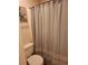 View of neutral colored bath/shower with gray curtain and toilet at 424 Village Way, Loganville, GA 30052