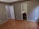 A bedroom with a light wood floor and access to the bathroom and closet through open doors at 6579 Alford Way, Lithonia, GA 30058